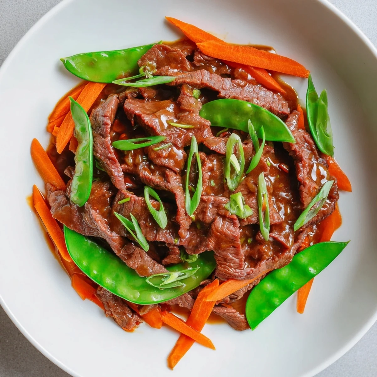A sizzling wok of beef stir fry with snow peas and carrots, showcasing vibrant veggies and flavorful beef.
