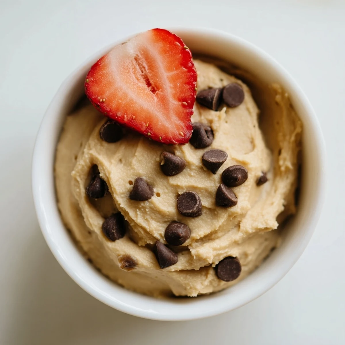 Easy to make, this gluten-free Chocolate Chip Cookie Dough Hummus looks thick and creamy in a serving dish ready for snacking.