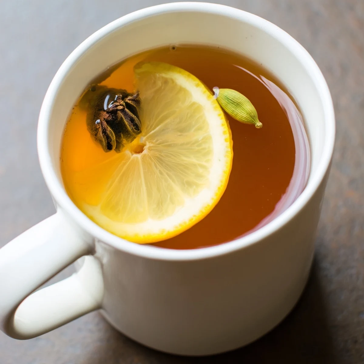 Clear glass teapot displaying Spiced Tea with Lemon brewed with ginger, cinnamon, and cardamom pods.