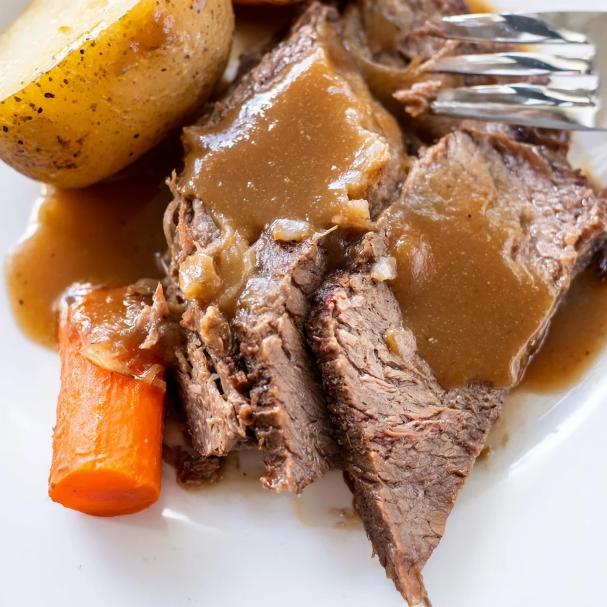 Golden brown Slow Cooker Pot Roast with Gravy ladled over root vegetables, steam rising from the meat.