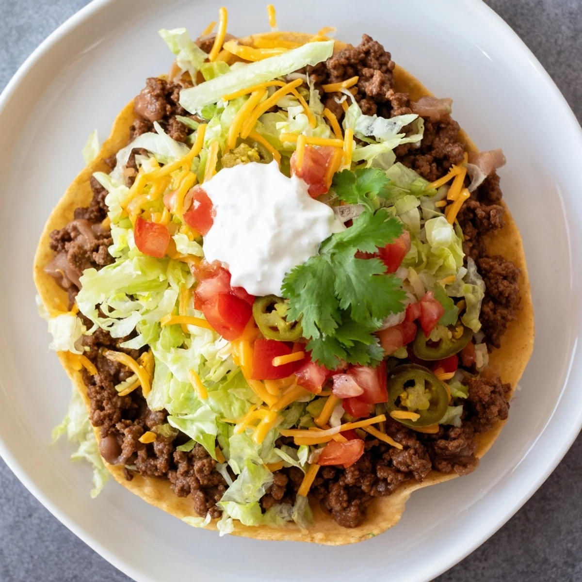 Spicy jalapeños and zesty lime wedges garnish these easy Beef Tostadas with Refried Beans.