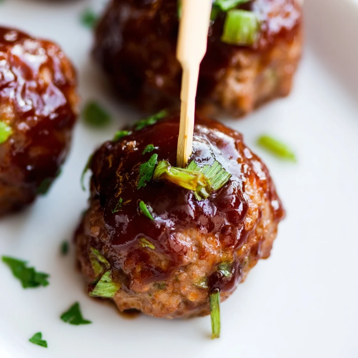 Golden-brown turkey appetizer meatballs glazed in a shiny, tangy-sweet barbecue sauce, garnished with fresh parsley on a rustic platter.