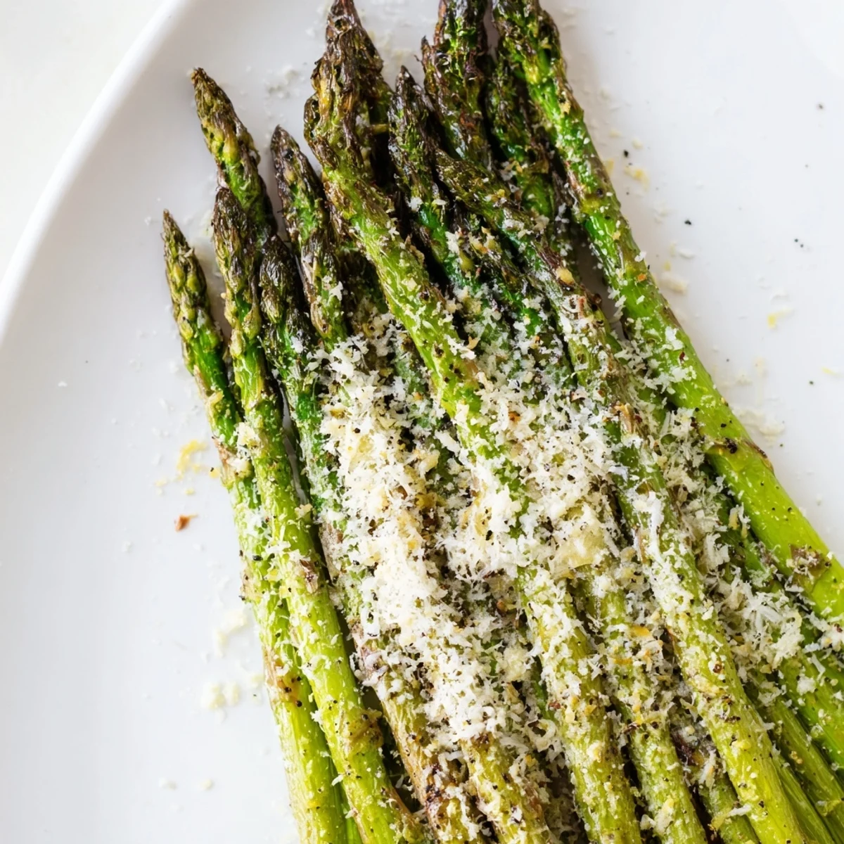 Elegant Roasted asparagus with Parmesan and lemon side dish plated with lemon wedges, ideal for pairing with grilled chicken.