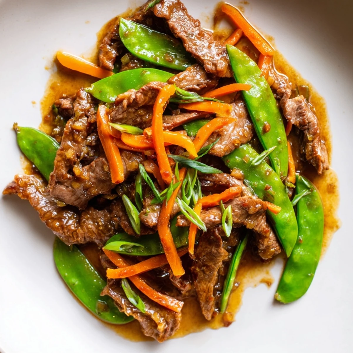 A family-style platter of Beef Stir Fry with Snow Peas and Carrots, loaded with fresh vegetables and juicy beef, ready to serve over a bowl of steamed white rice.