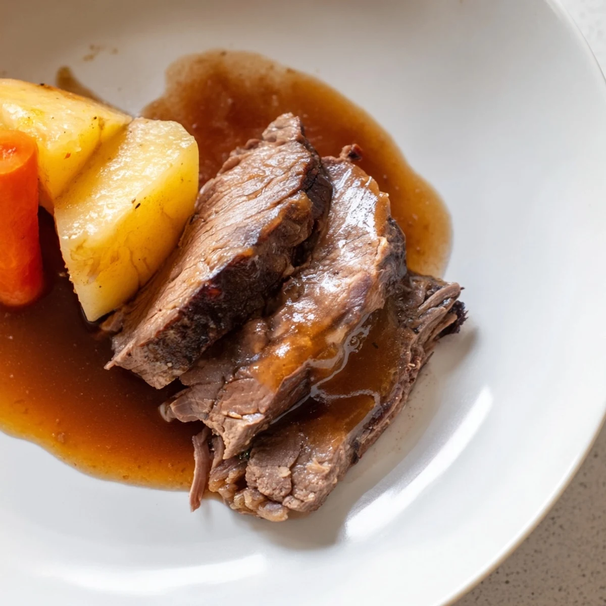 Golden-brown Slow Cooker Pot Roast with Carrots and Potatoes, served on a platter with rich gravy.