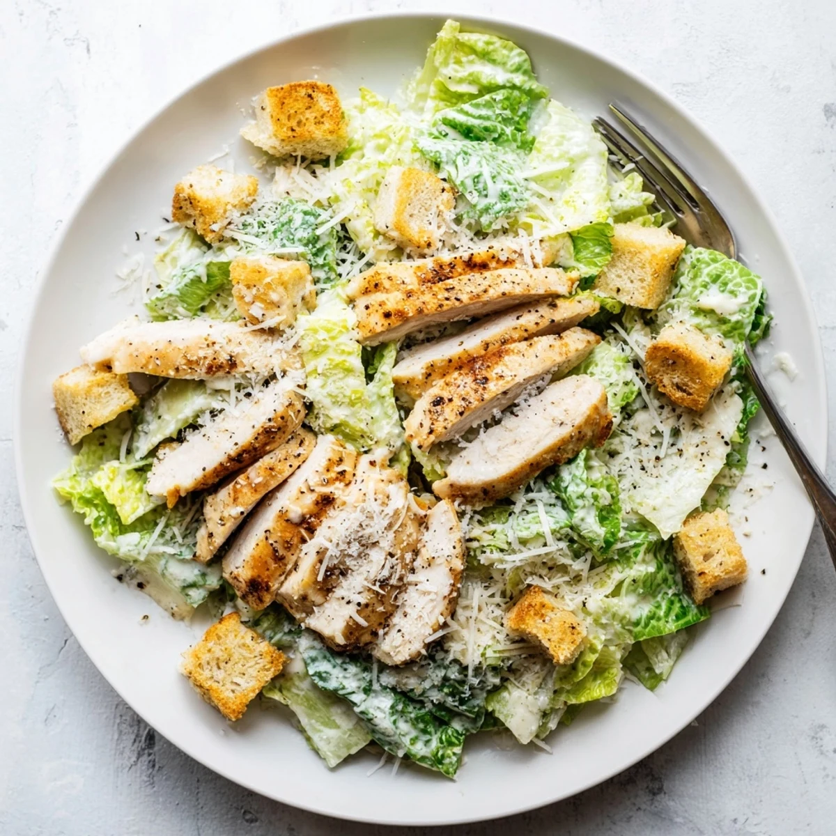 Homemade croutons add a crunchy texture to this classic Chicken Caesar Salad, featuring juicy grilled chicken and freshly grated Parmesan cheese.