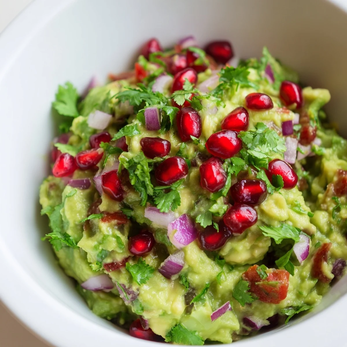 Bowl of homemade Touchdown Spicy Guacamole with diced red onion, tomatoes, and jalapeños, served with tortilla chips.