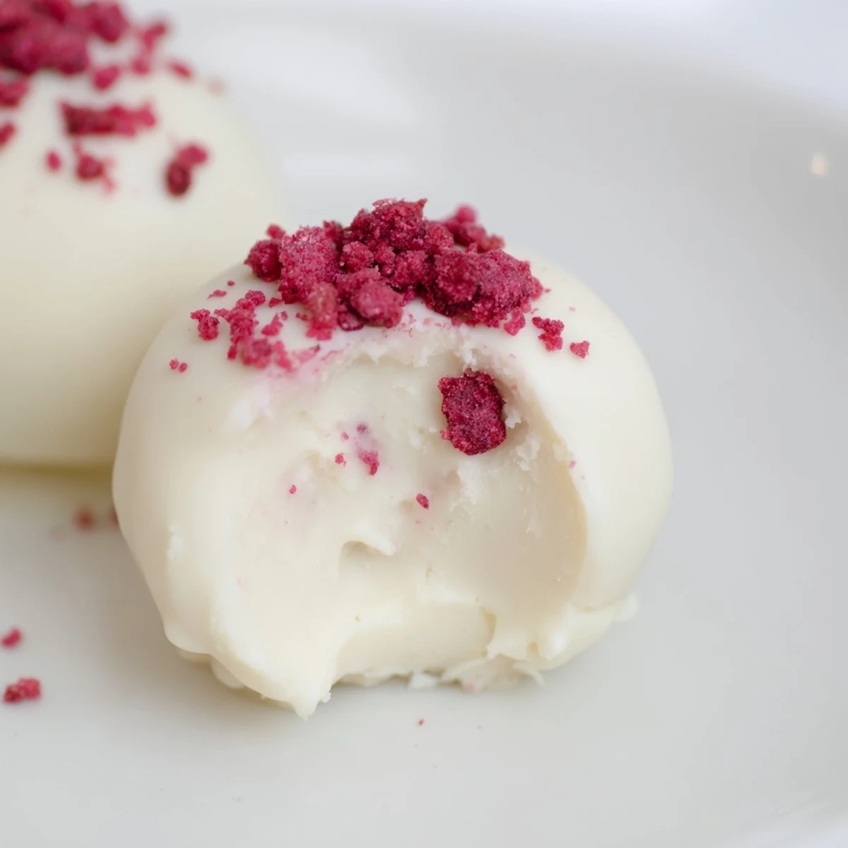 Homemade White Chocolate Raspberry Truffles arranged on a parchment-lined tray, showcasing their smooth white chocolate coating and rich texture.