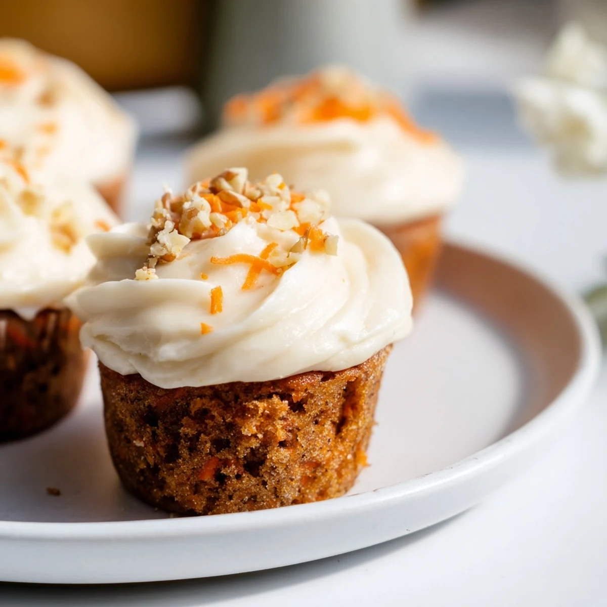 Moist carrot cake cupcakes crowned with silky cream cheese frosting, topped with a delicate sprinkle of cinnamon.  