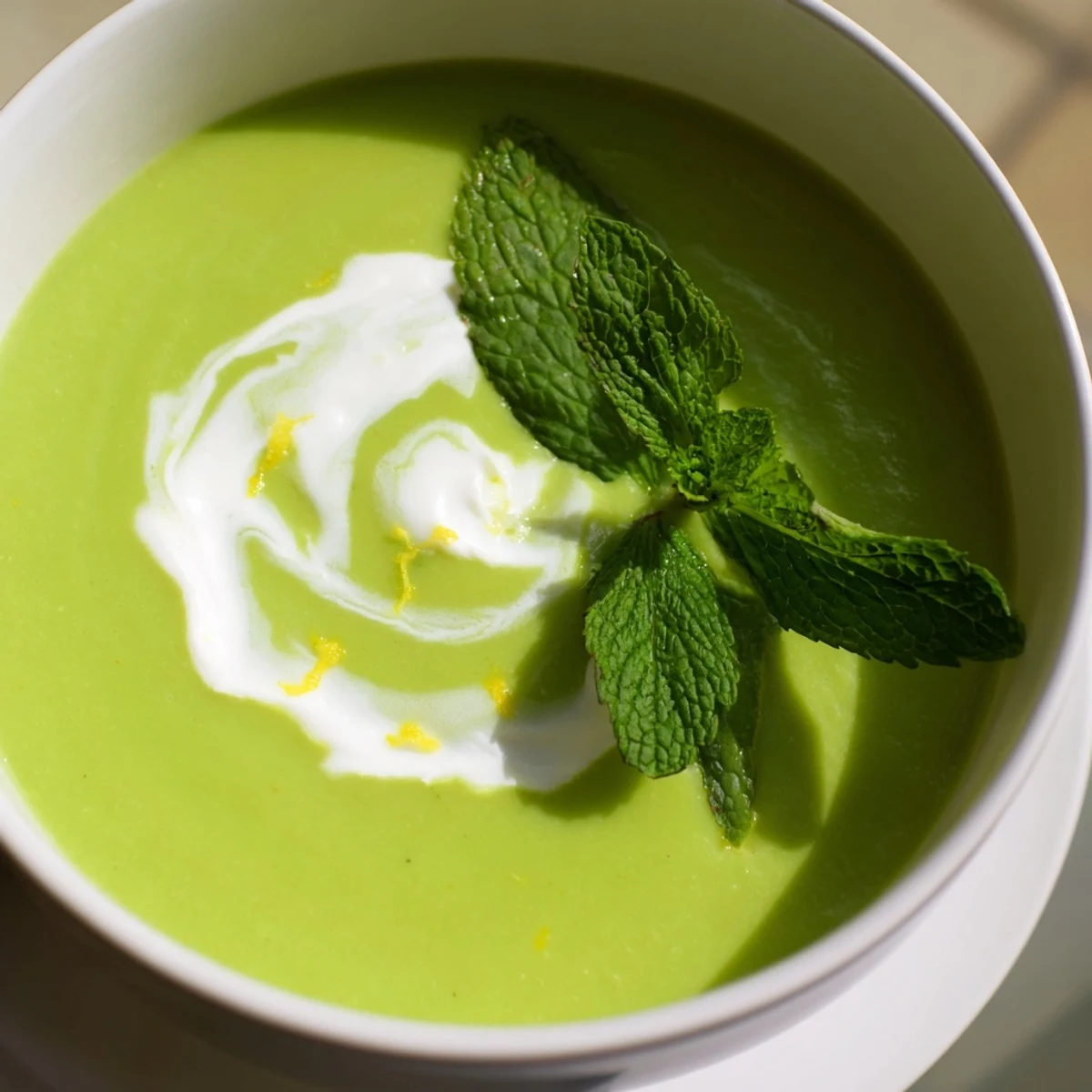Vibrant green Creamy Spring Pea and Mint Soup with Crème Fraîche served in a rustic ceramic bowl, steam rising from the silky surface.