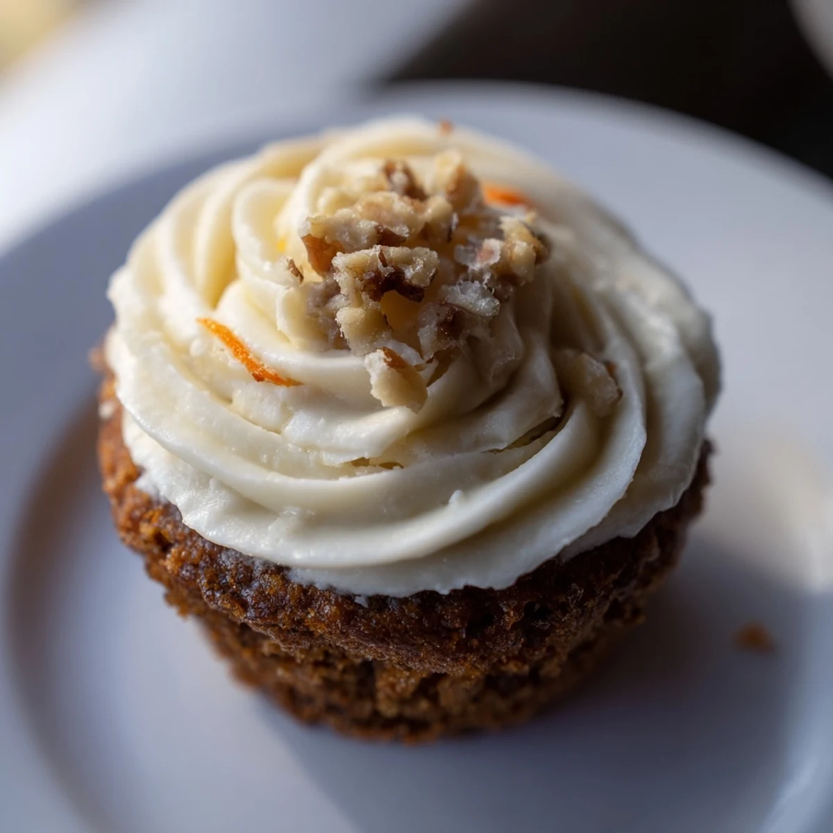 Freshly baked Carrot Cake Cupcakes with Cream Cheese Frosting and a sprinkle of cinnamon served on a dessert stand.