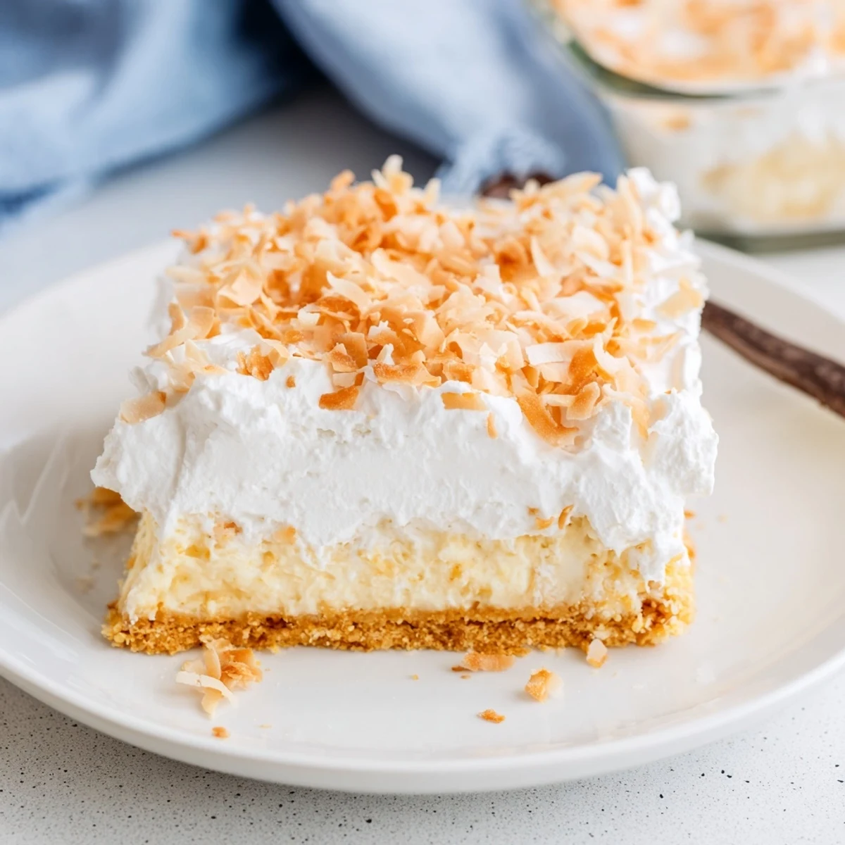 Freshly sliced Coconut Cream Dream Bars feature velvety coconut cream and toasted flakes on a white plate.