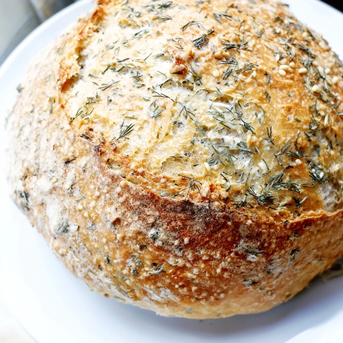 Golden-brown No-Knead Dill Gouda Artisan Bread with a rustic crust, fresh herbs, and creamy cheese on a cutting board.  