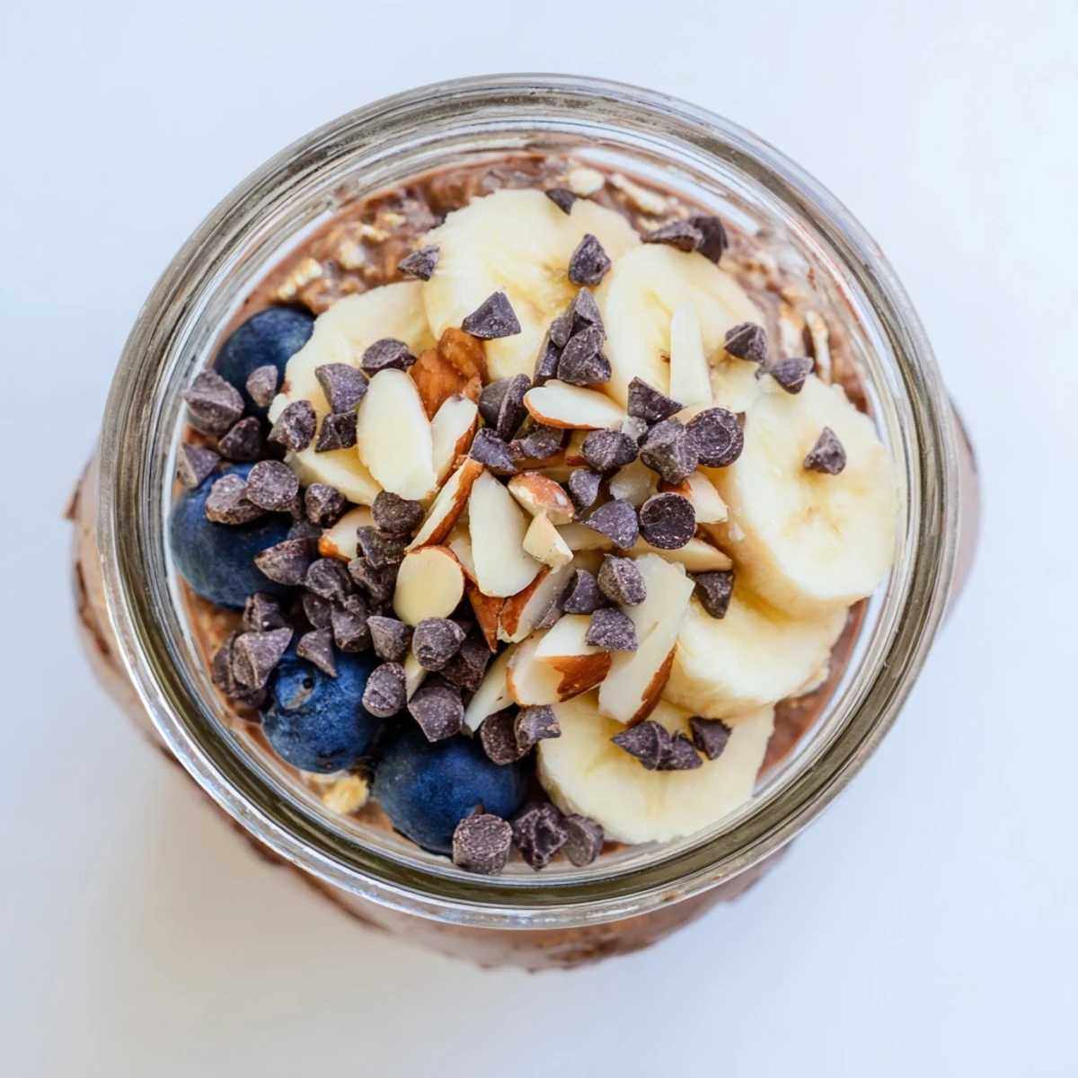 Ultimate Healthy Chocolate Overnight Oats topped with chopped almonds, fresh berries, and a drizzle of maple syrup.