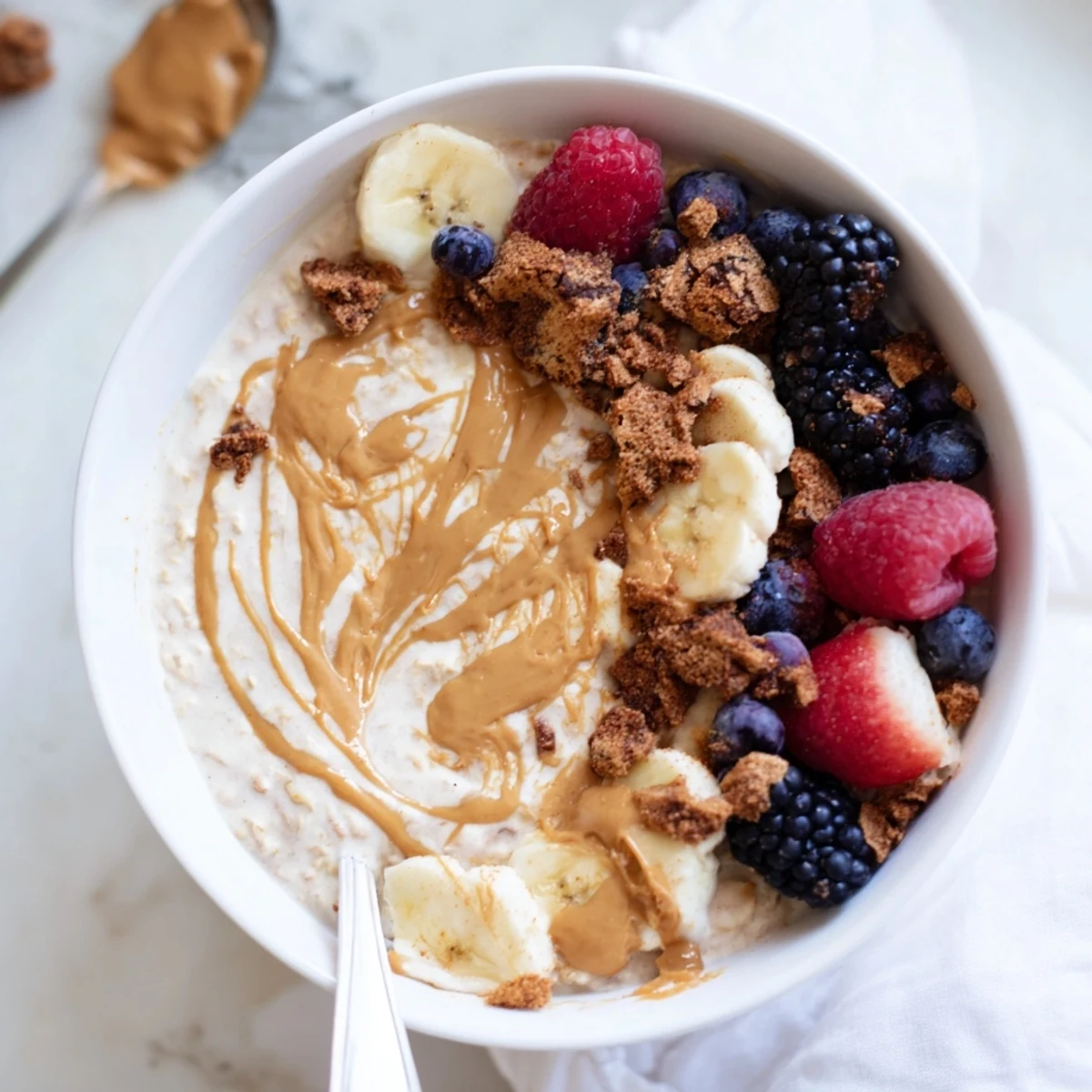 A spoonful of Quick Biscoff Overnight Oats showing a creamy texture with banana slices and a drizzle.  