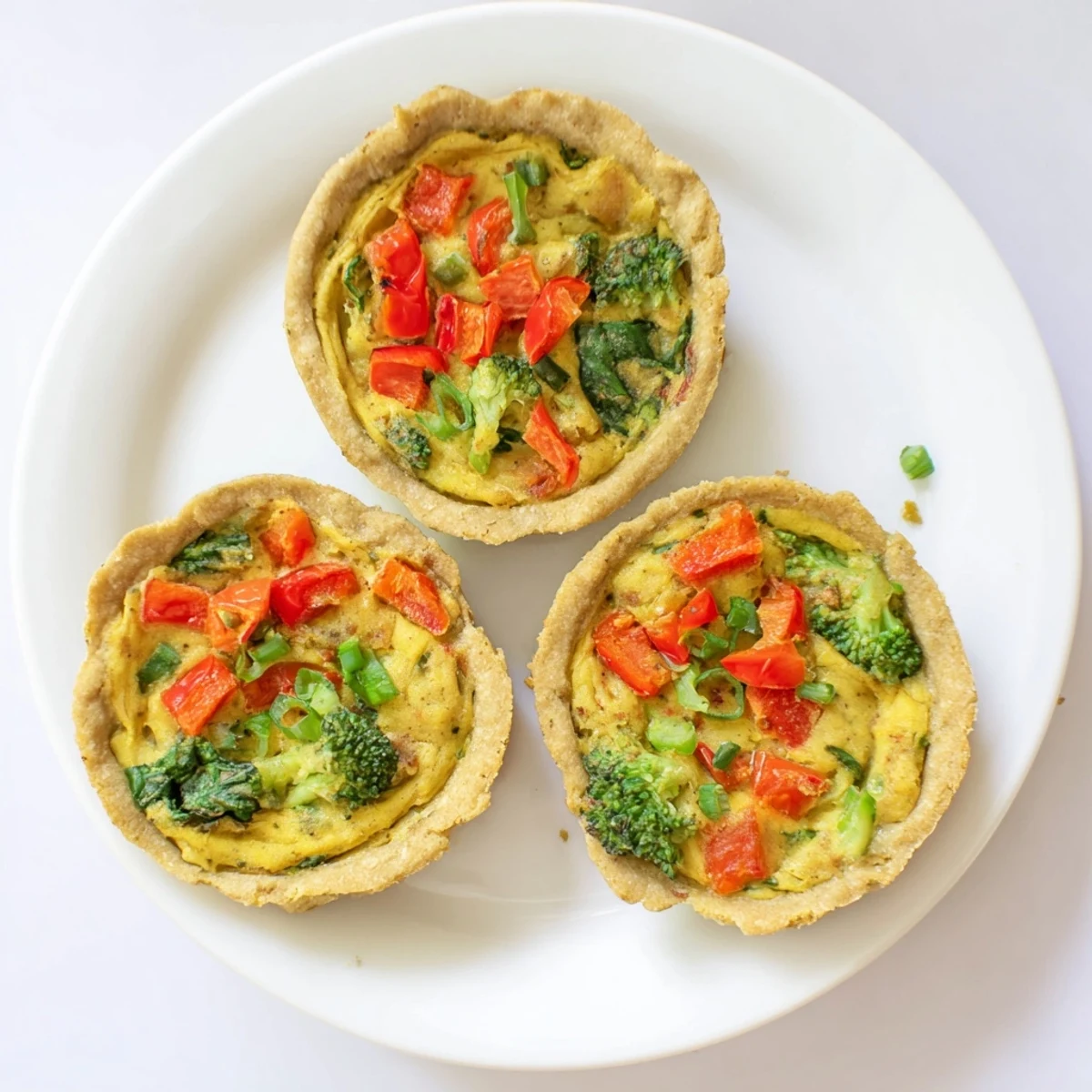 Savory vegan mini quiches with golden crust and broccoli pieces, perfect for a healthy brunch snack.