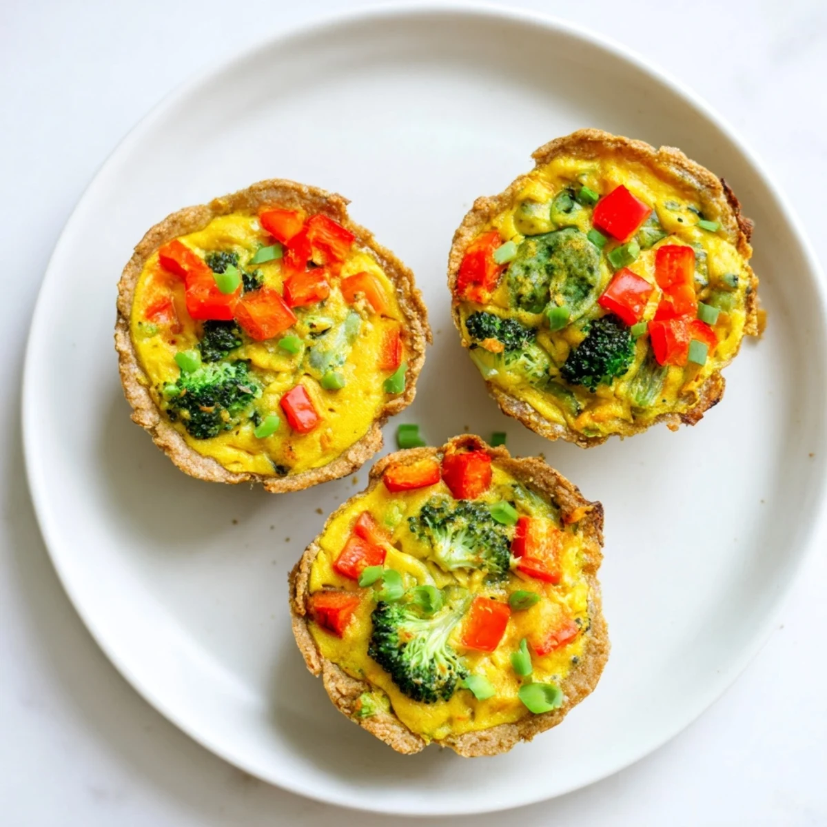 Freshly baked vegan mini quiches with chickpea filling, served warm on a rustic wooden board.  