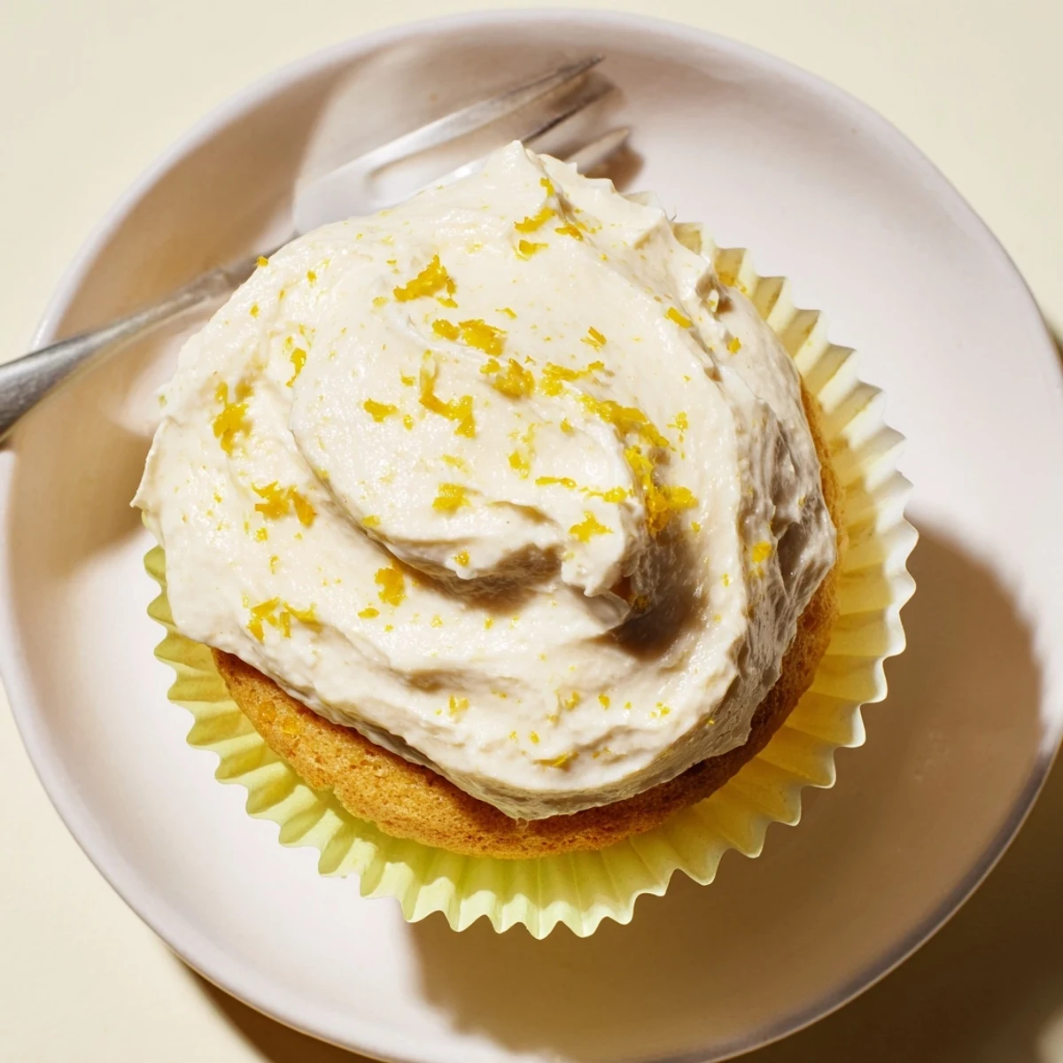 Moist golden Limoncello cupcakes topped with swirls of creamy lemon frosting and fresh zest.