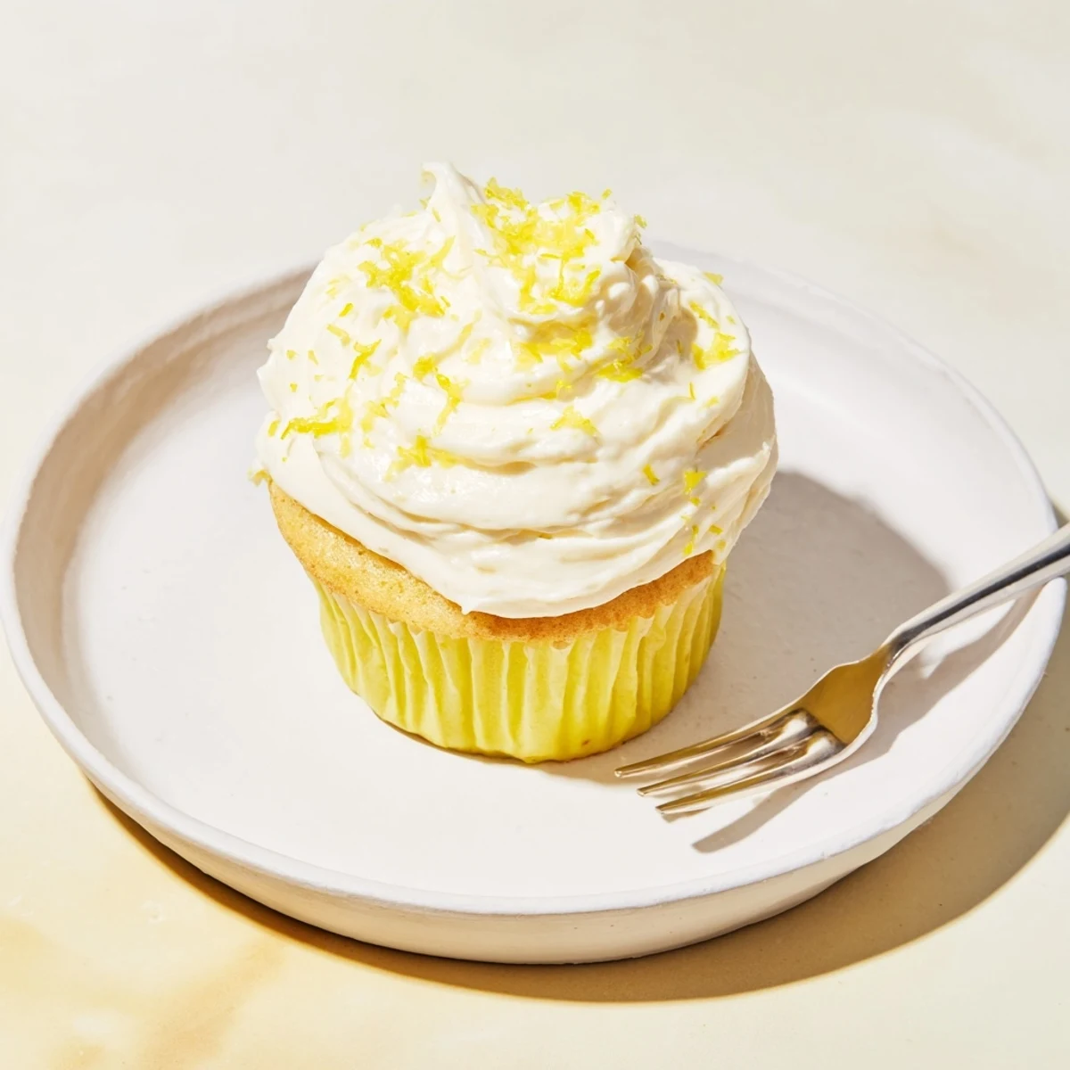 Bright Limoncello cupcakes with zesty lemon glaze and fluffy frosting on a rustic wooden board.