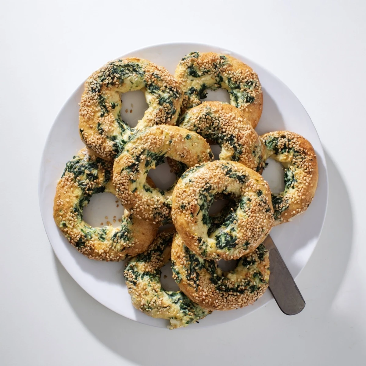 Freshly baked Spinach Cottage Cheese Flagels topped with sesame seeds on a cooling rack, perfect for a savory breakfast.