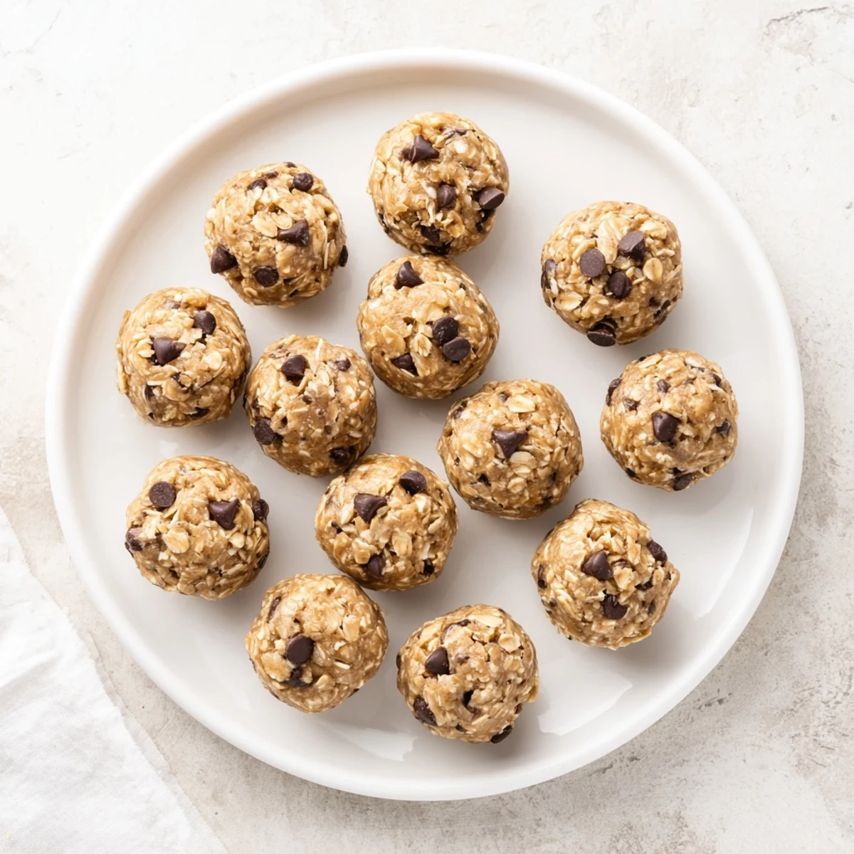 Chilled No Bake Peanut Butter Energy Bites are served on a tray with mini chocolate chips and oats.