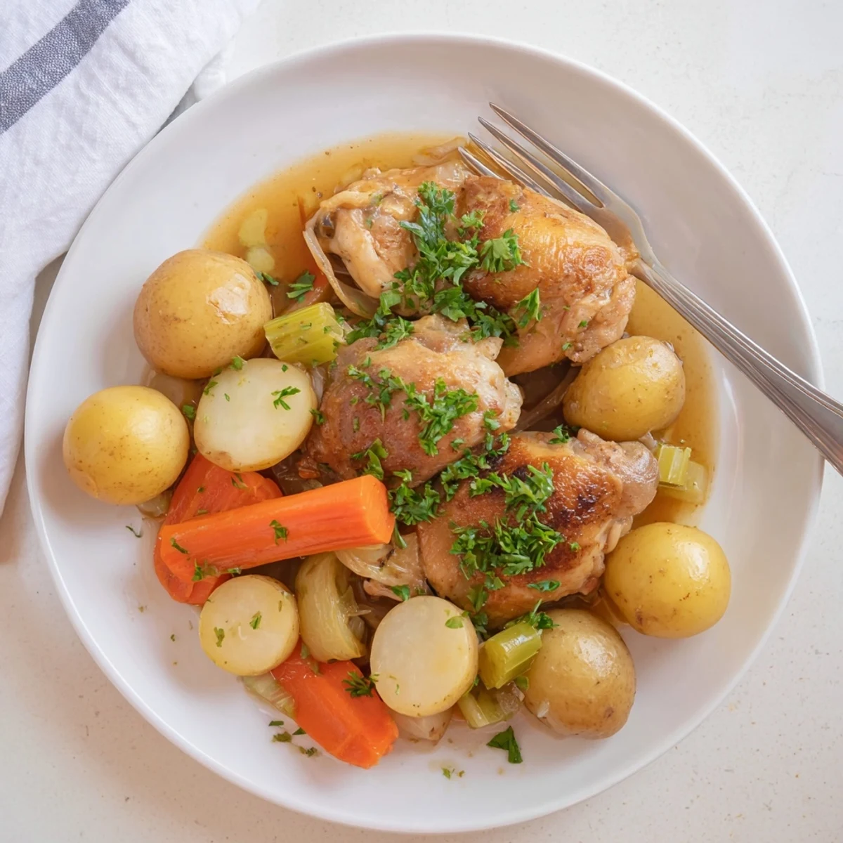 A close-up of tender Slow Cooker Chicken over baby potatoes and carrots, perfect for a family dinner.