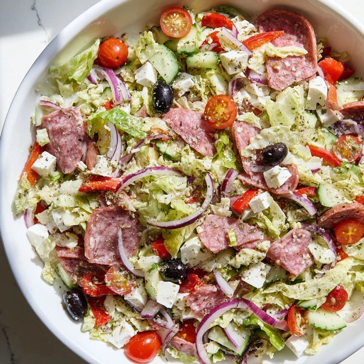 Colorful Italian chopped salad bowl with crisp vegetables, salami, mozzarella and tangy homemade dressing