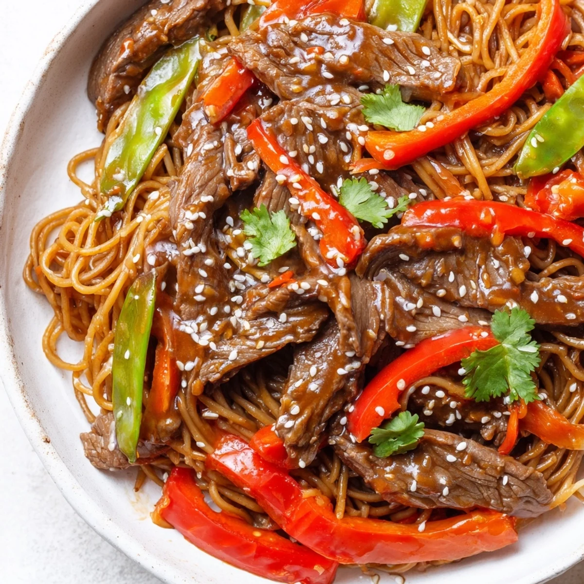 Tender beef strips tossed with chewy noodles and vibrant bell peppers in glossy sauce