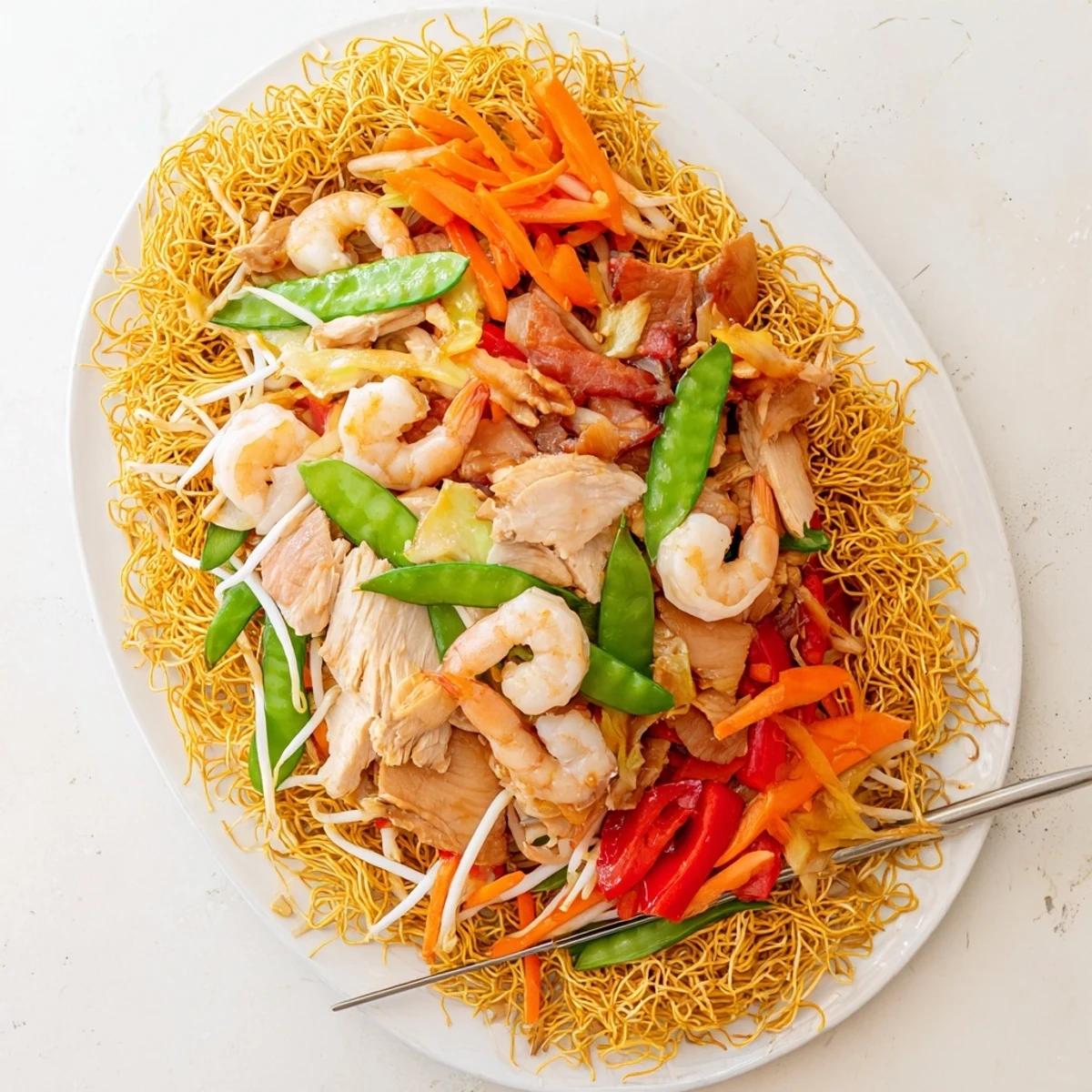 Steaming plate of Cantonese chow mein featuring crunchy noodles with shrimp chicken and tender-crisp bell pepper strips