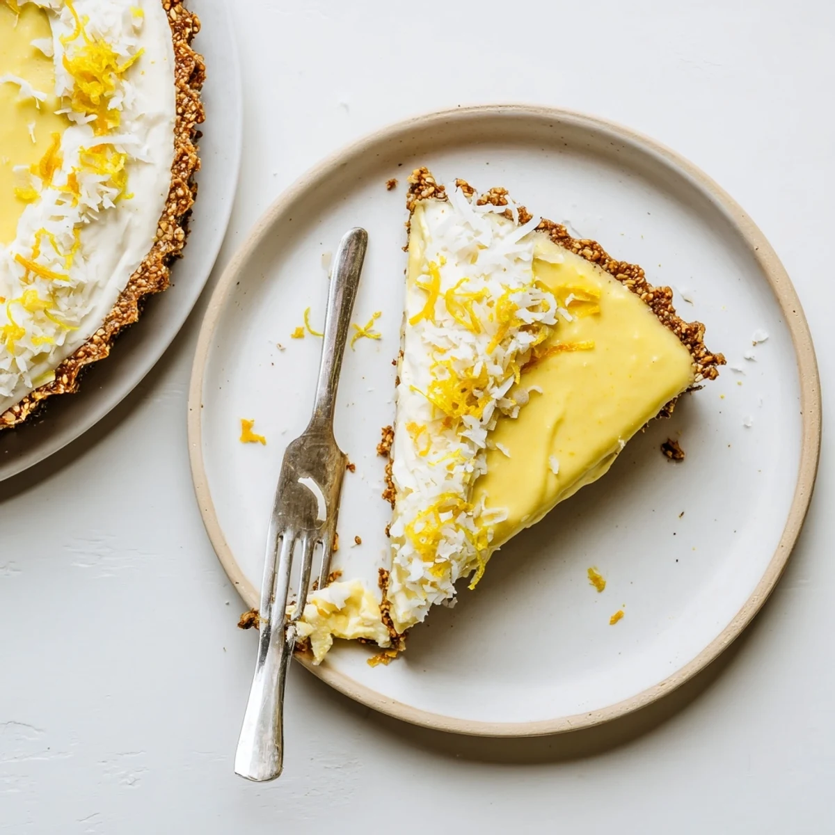 Slice of refreshing no bake vegan lemon tart garnished with fresh lemon zest