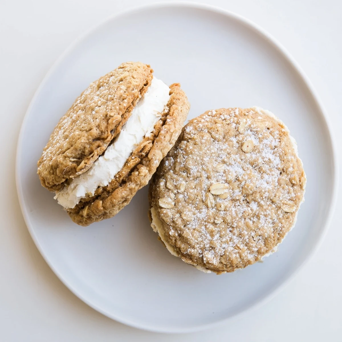 Two soft homemade oatmeal cream pies with vanilla frosting sandwiched between chewy spiced cookies