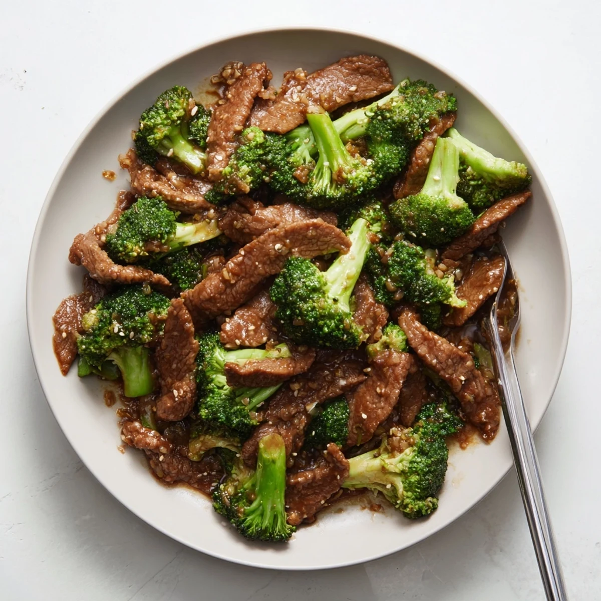 Glossy homemade beef and broccoli stir fry sauce ladled over sizzling beef and crisp broccoli