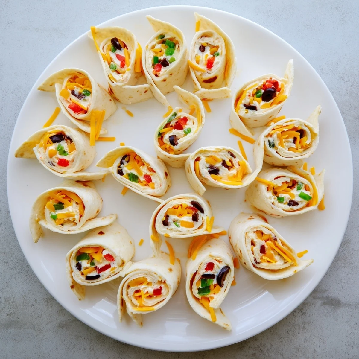 Bite-sized easy tortilla pinwheels arranged on a party tray showcasing their vibrant vegetable-filled cream cheese centers