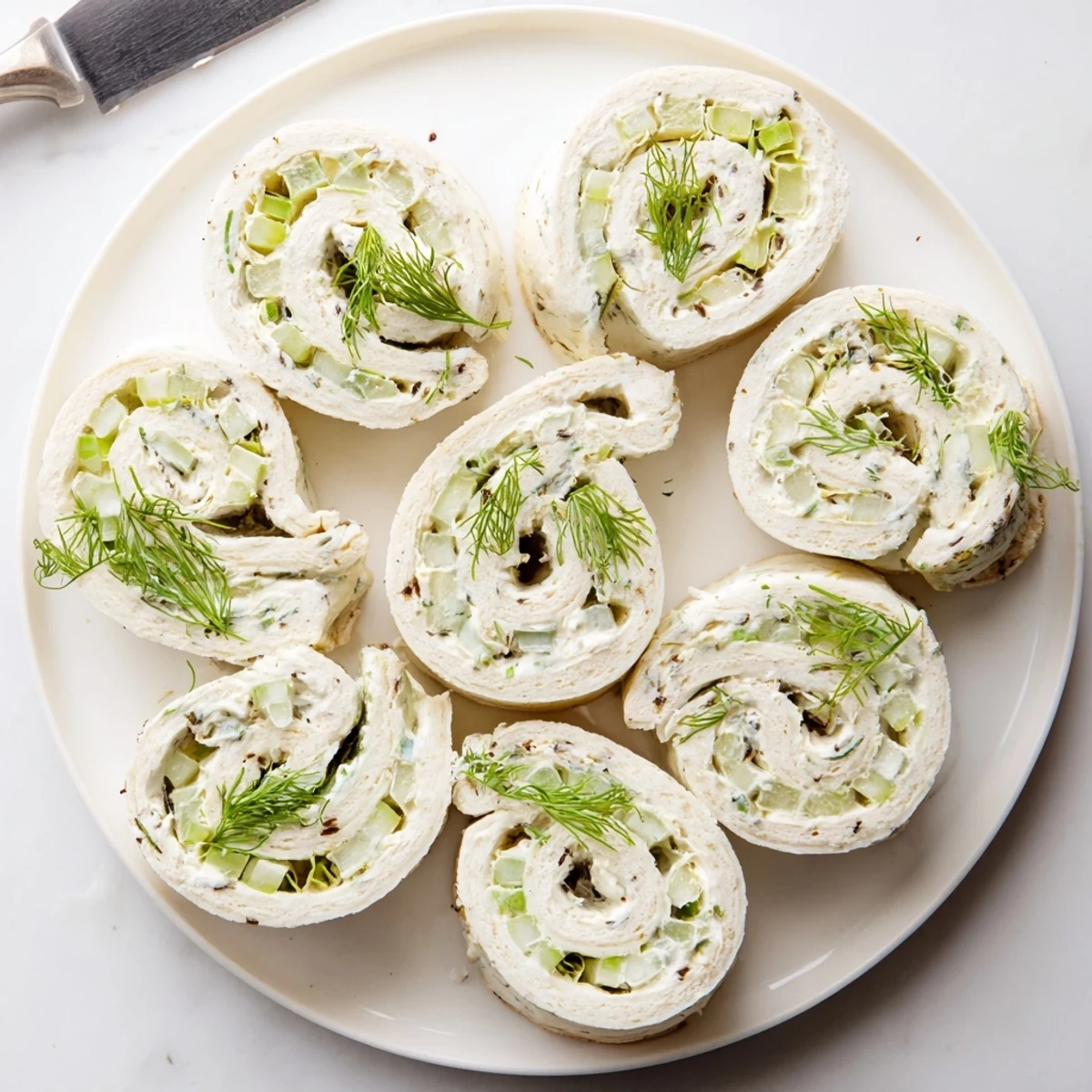 Creamy pickle dip pinwheels rolled in soft flour tortillas with green onion speckles
