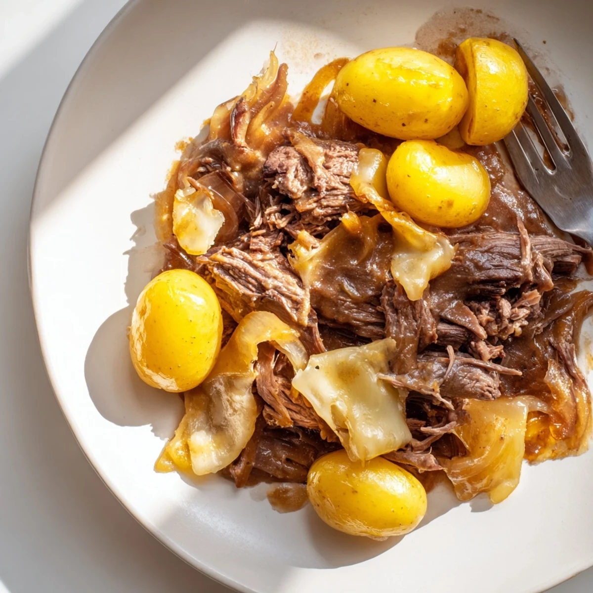 Tender French onion pot roast with caramelized onions and melted Gruyère cheese in a rich dark gravy