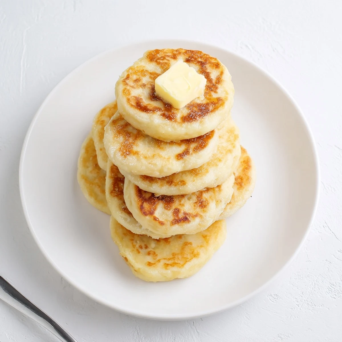 Golden brown Irish potato cakes stacked on a wooden serving board with melted butter pooling on their crispy exteriors