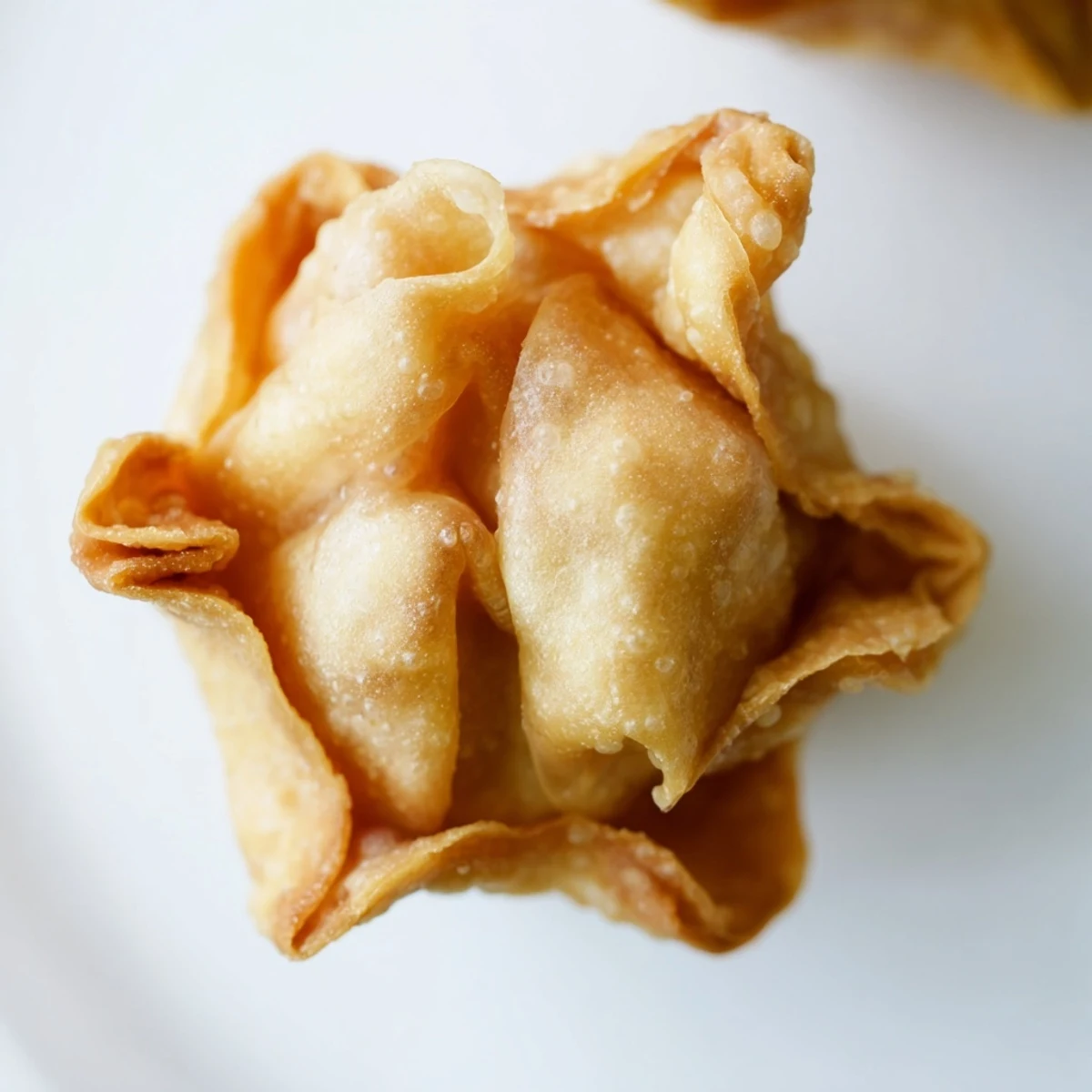 Golden fried Crab Rangoon Bombs with creamy crab cheese filling served on white plate