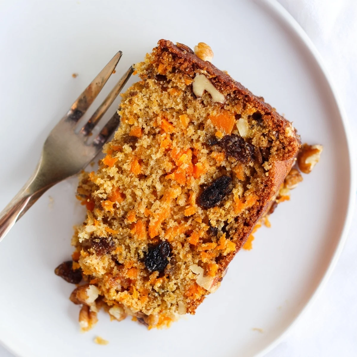 Moist Greek yogurt carrot cake baked in a round pan with freshly grated carrots visible throughout the tender crumb