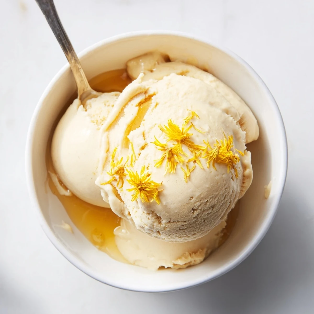 Creamy dandelion honey ice cream scoop drizzled with golden honey and fresh petals
