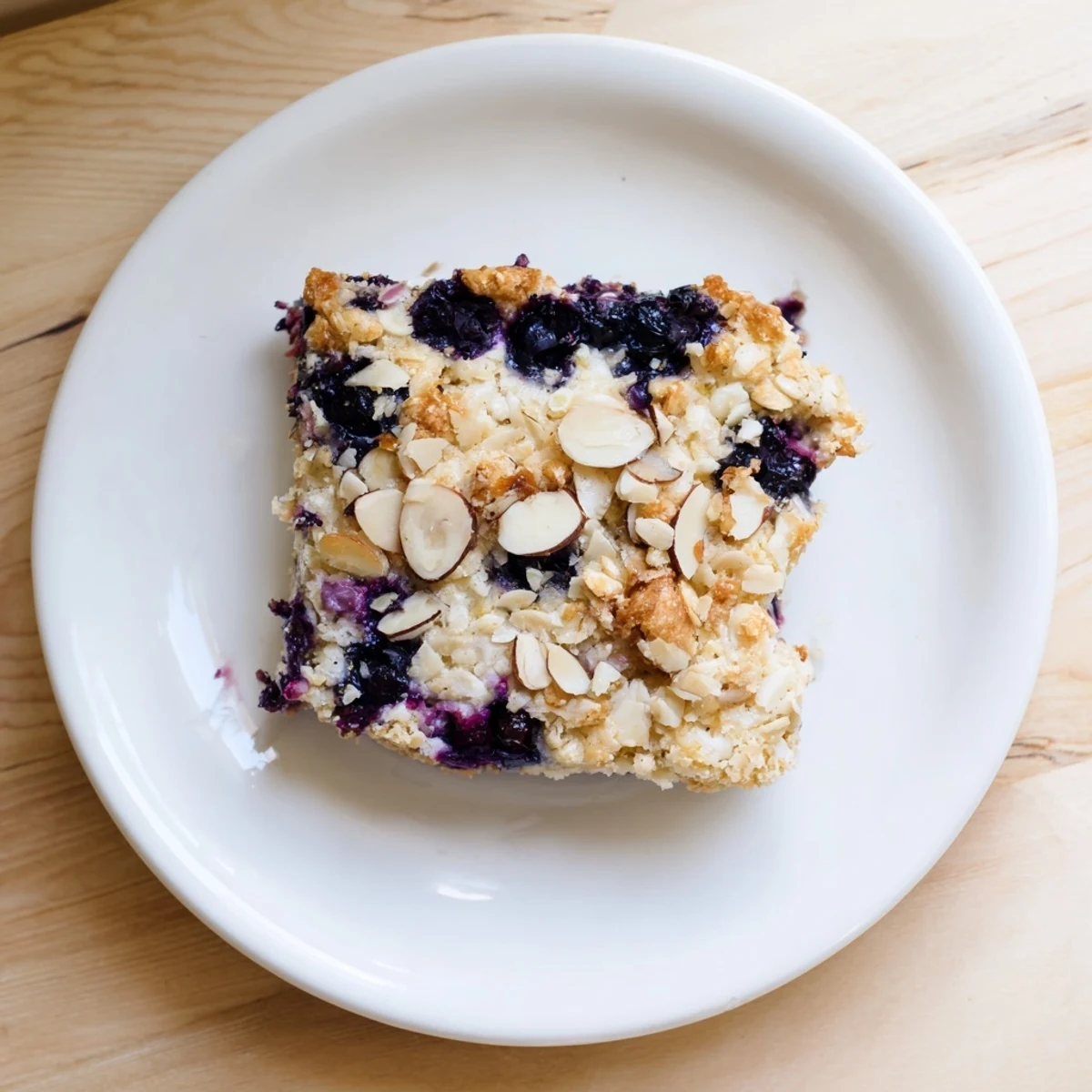 Sliced square of warm blueberry cottage cheese breakfast bake topped with fresh berries and maple drizzle