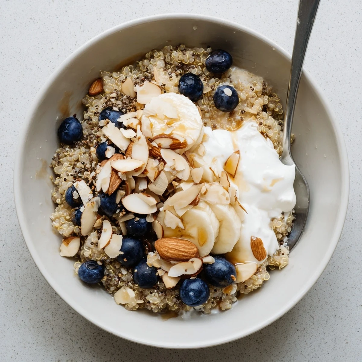 Creamy blueberry quinoa breakfast bowl topped with fresh fruit, crunchy nuts, and coconut flakes