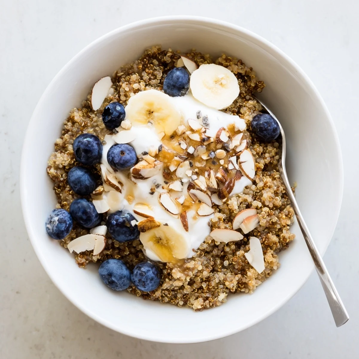 Golden quinoa breakfast bowl layered with sweet blueberries, chia seeds, and maple drizzle