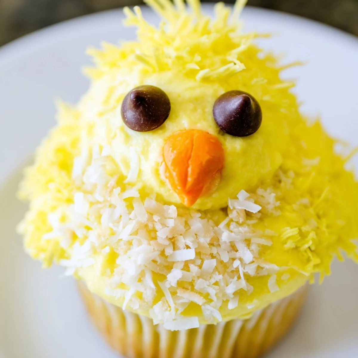 Adorable Easter Chick Cupcakes with fluffy yellow frosting and candy faces on white serving platter