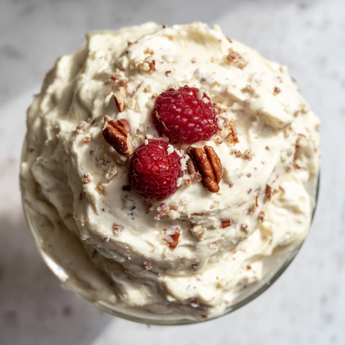 Light and airy keto cheesecake fluff swirled in a bowl with berry garnish