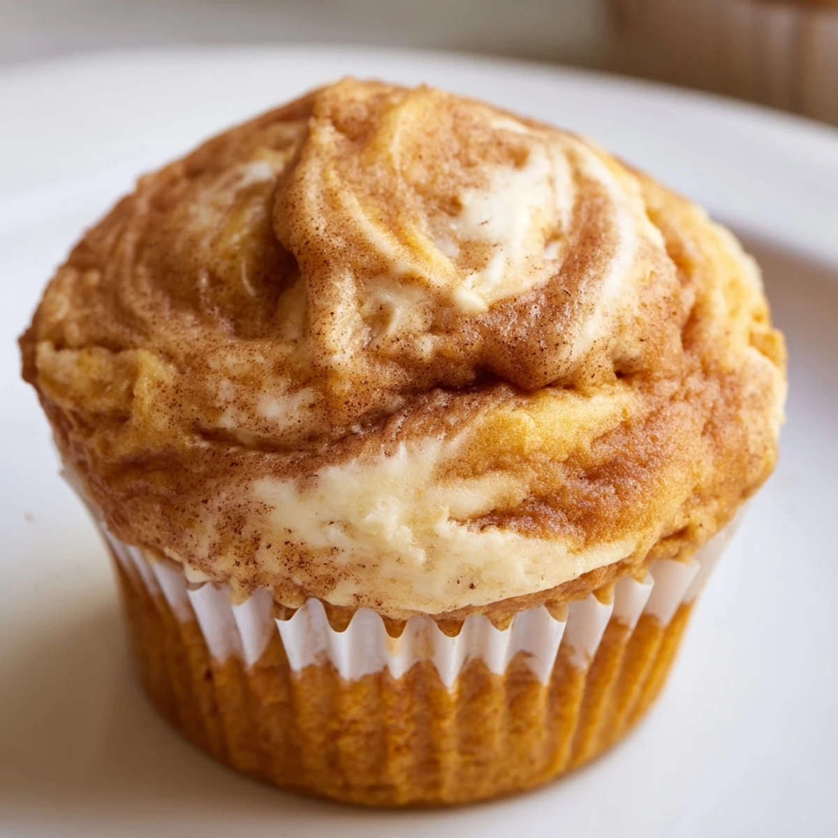 Golden chai pumpkin cheesecake muffins with creamy swirled tops on a cooling rack