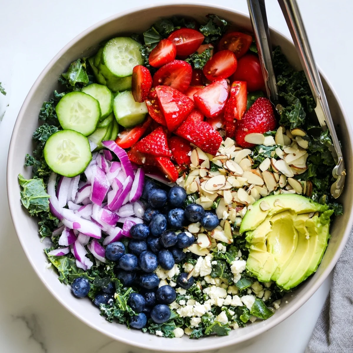 Hearty summer kale salad with juicy strawberries, avocado, and toasted almonds