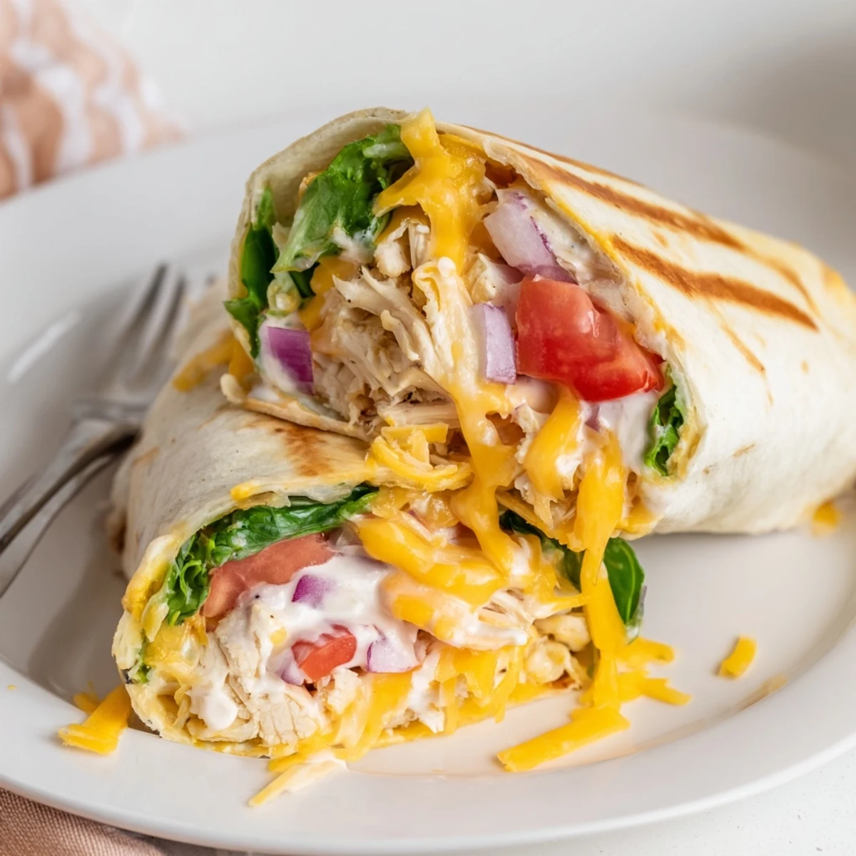 Family-style Cheesy Garlic Chicken Wraps packed with juicy chicken, tomato, and tangy sauce.