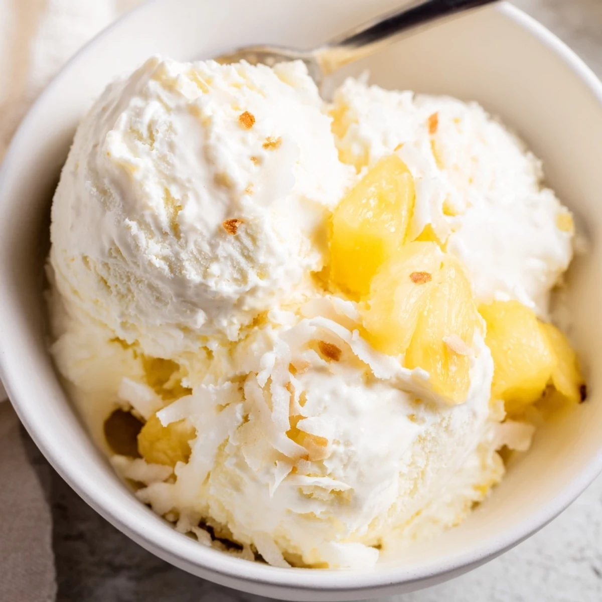 Creamy Pineapple Ice Cream topped with toasted coconut and rum drizzle.
