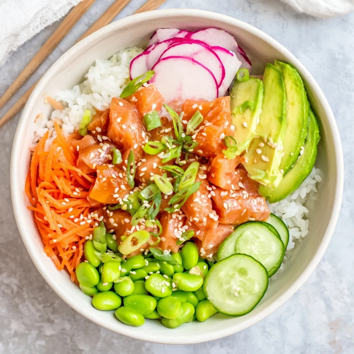 Healthy salmon and avocado poke bowl topped with sesame seeds and savory sauce