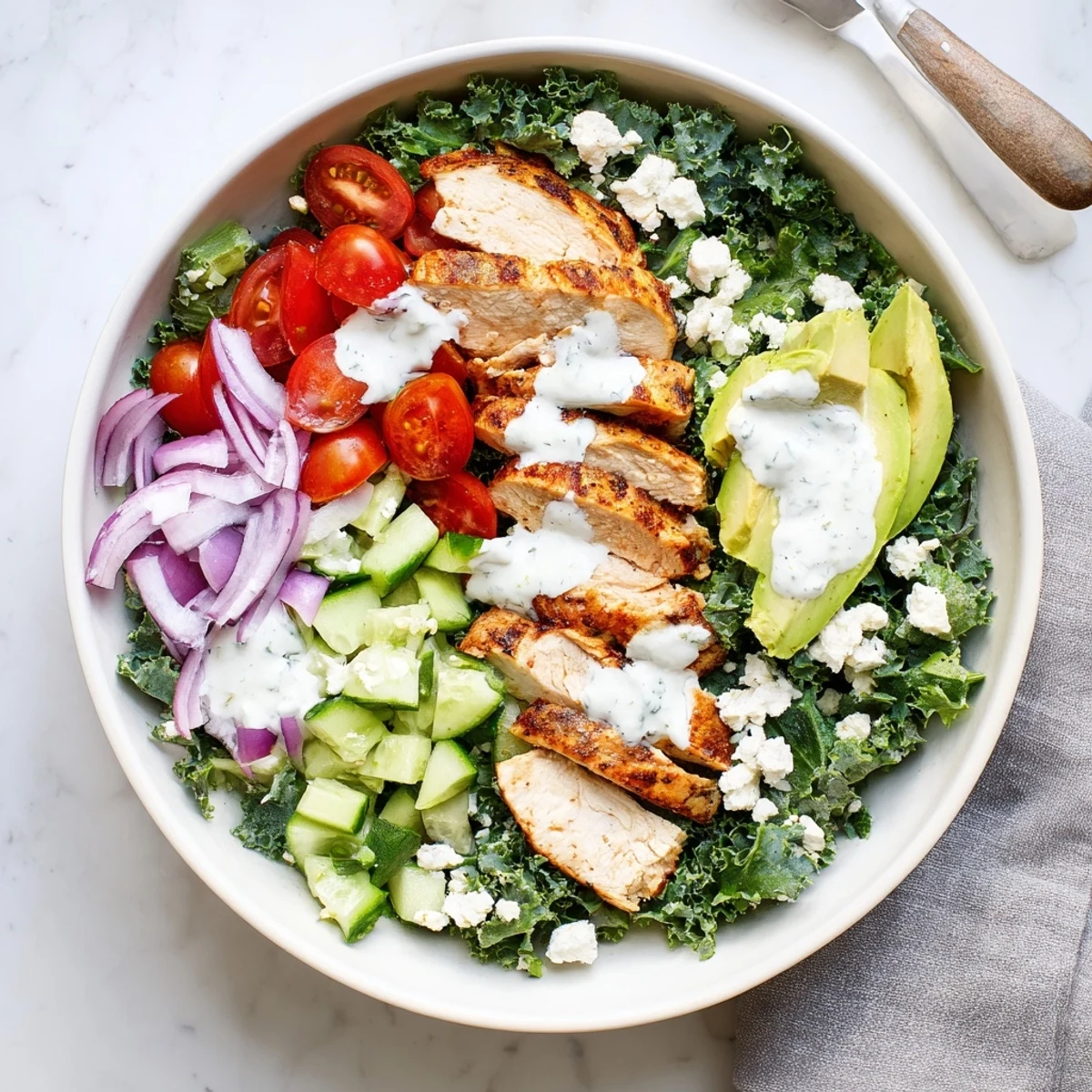 Colorful marinated kale and chicken bowl with fresh vegetables and creamy dressing